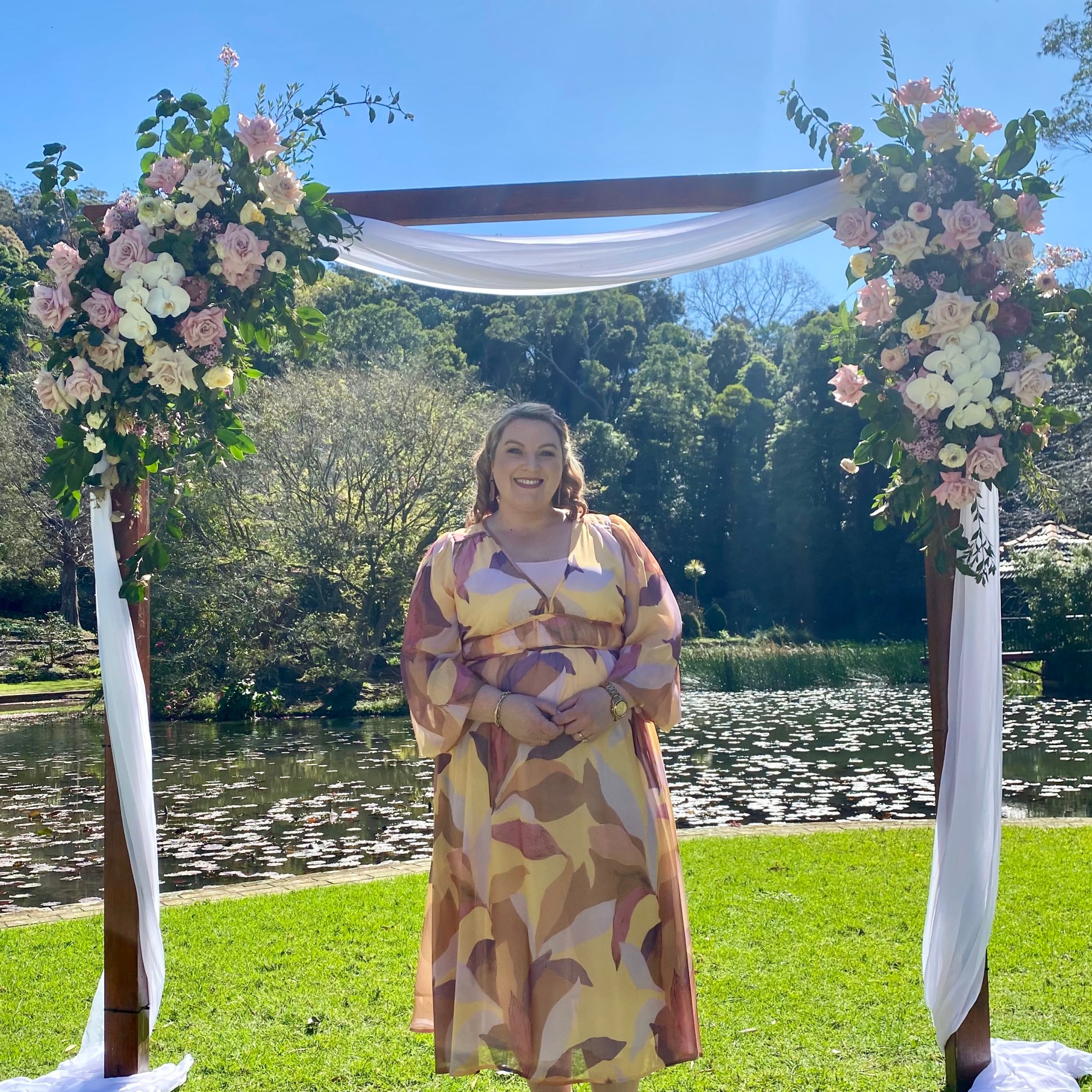 Celebrant standing in front of floral arbor in front of lake